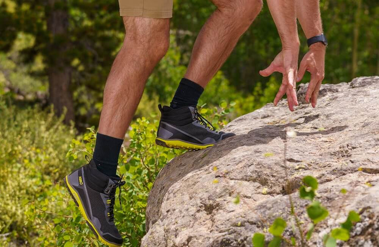 man climbing up rock with xero shoes