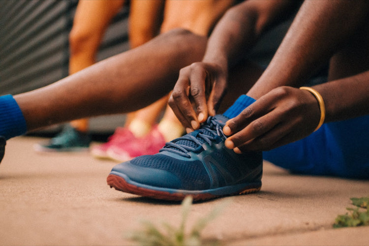 A person tying their Pacer Lite Xero Shoes shoe laces
